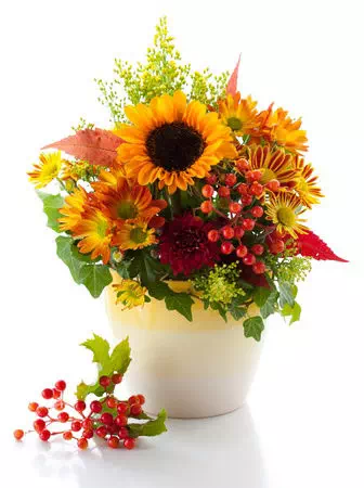 composition florale jaune et orange présentée dans un vase anti-renversement blanc