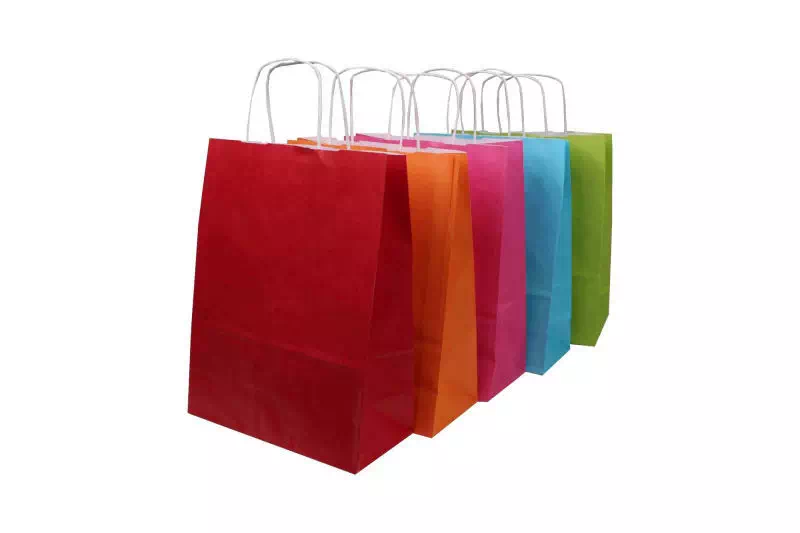 ensemble de sacs kraft de couleurs rouge, orange, rose, bleu, vert avec poignées torsadées blanches.
