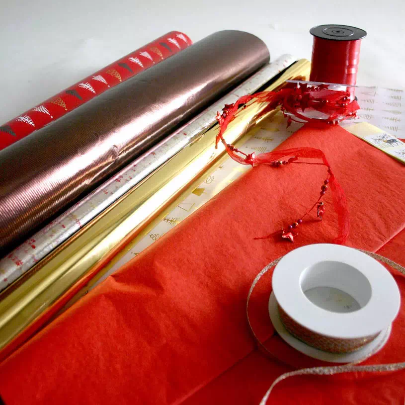 présentation de ruban, bolduc et noeud avec rouleau de papier cadeau et film métallisé.