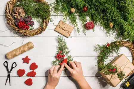 fleuriste qui décore une branche de sapin avec un noeud en satin rouge